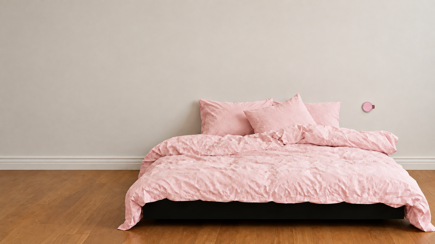 A Rosewood habit sticker on the bedroom wall beside a bed made up in pink linen.