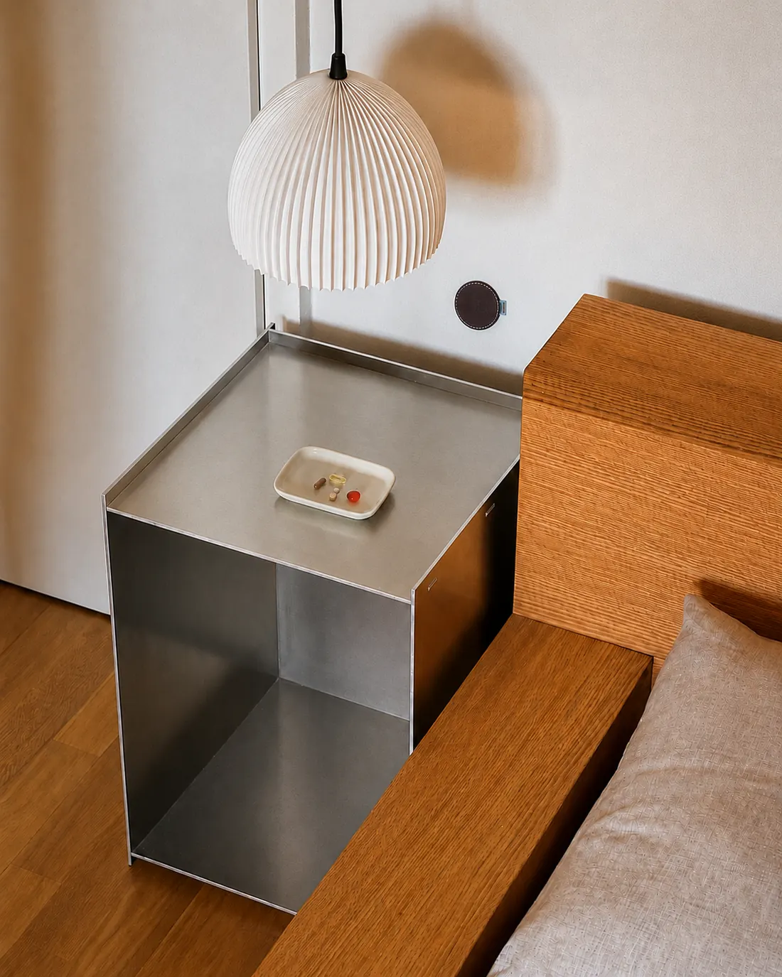 An Espresso habit sticker on the bedroom wall above a steel nightstand holding a small dish of vitamins.