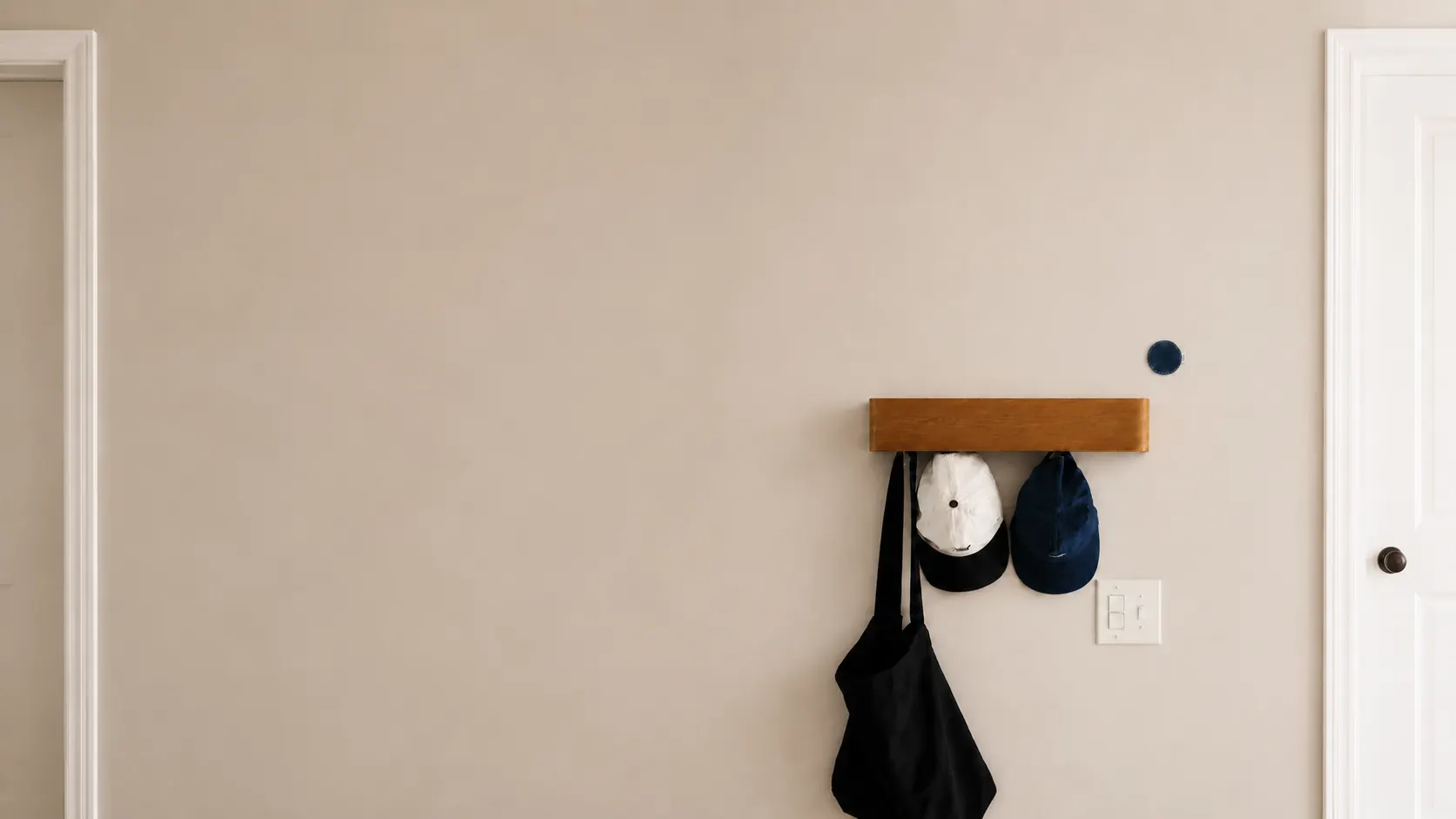 A Midnight habit sticker on the wall by the front door, above a rail of caps and a tote bag.